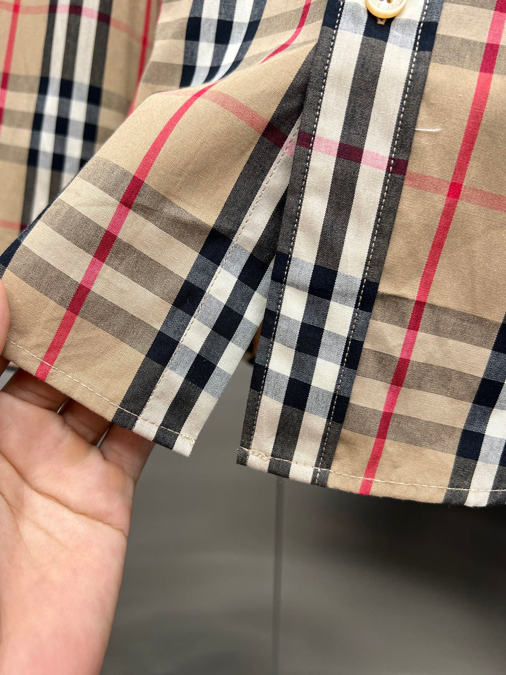 Plaid cuff and sleeve seam on button-up shirt, tan/black/red check pattern
