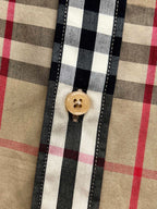 Round button and vertical placket on plaid shirt, tan/black/red check pattern