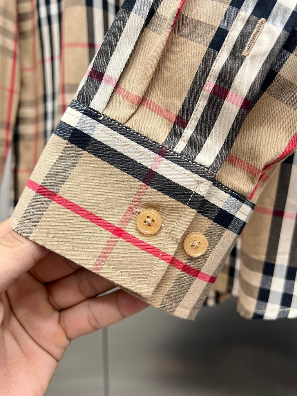 Burberry plaid long-sleeve shirt cuff with two tan buttons