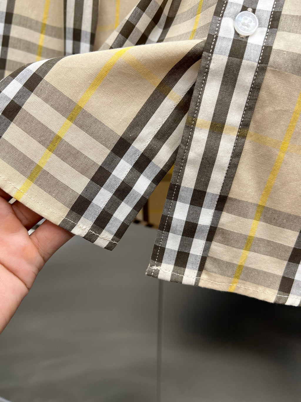 Plaid long-sleeve shirt cuff detail with buttons, cream base and black with yellow stripe checks