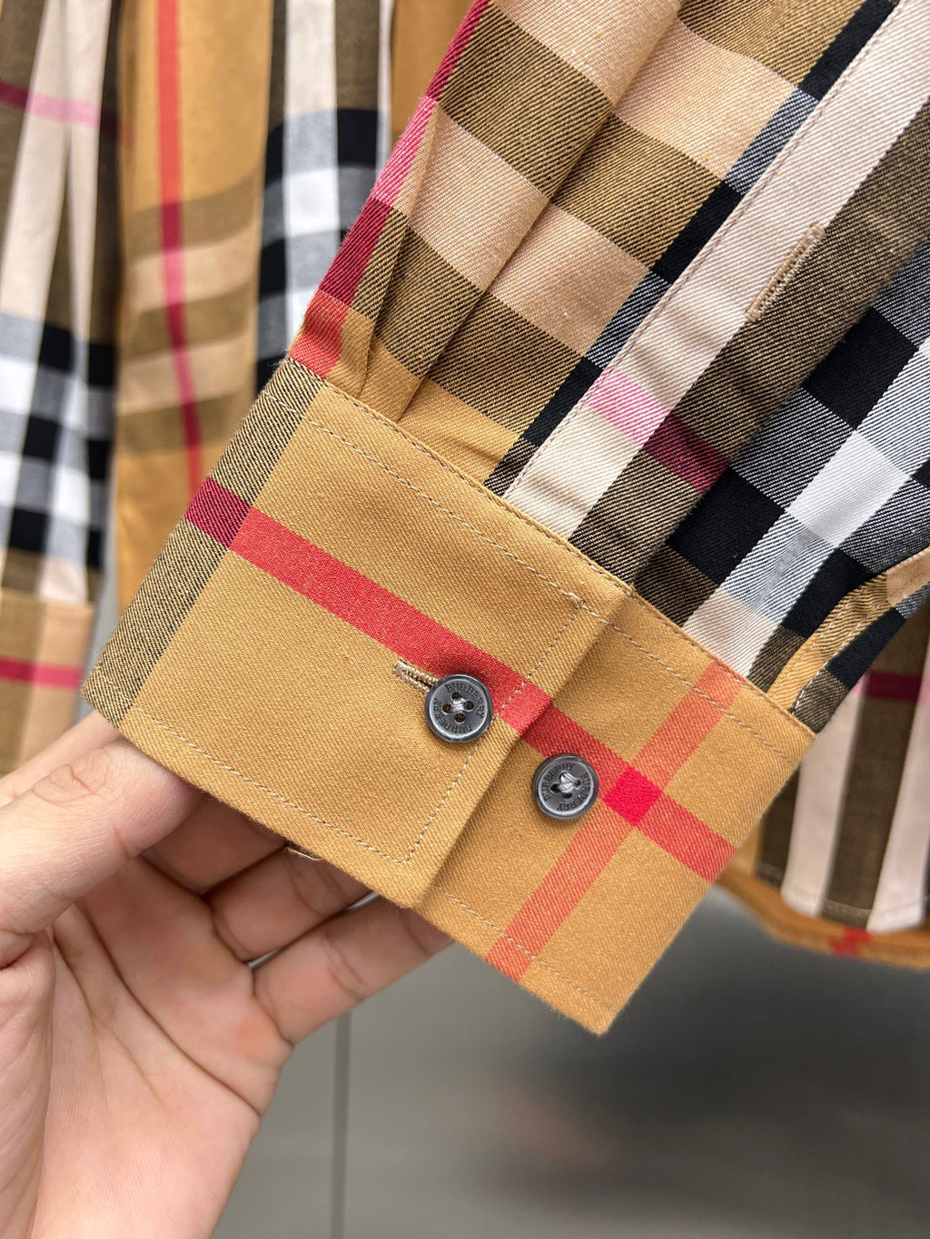 Burberry long-sleeve shirt cuff with two buttons and tan, red, black plaid
