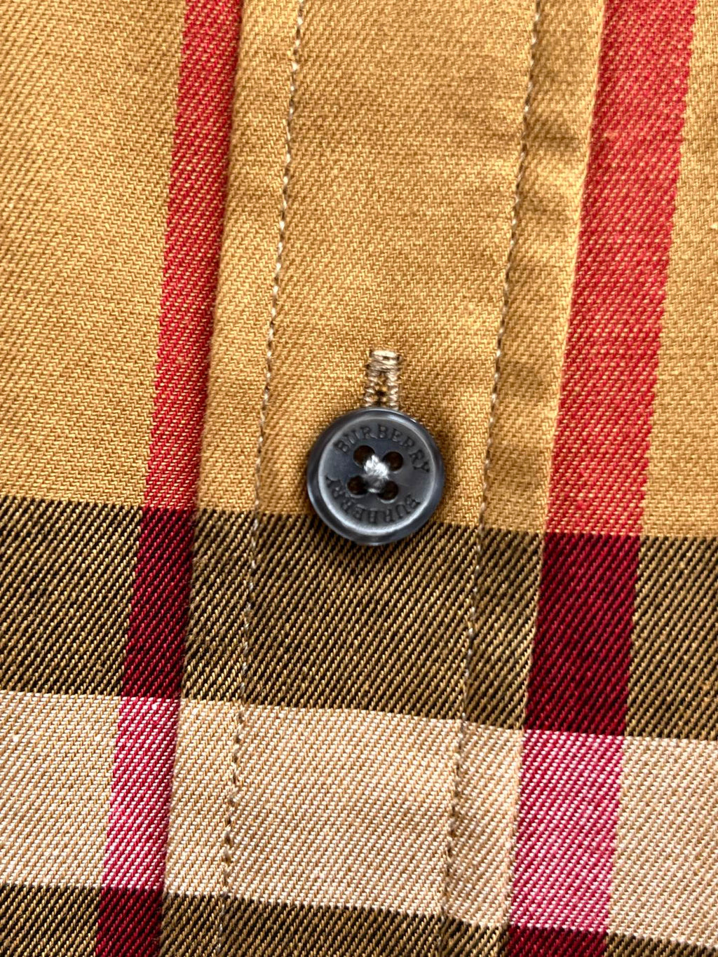 Round button on plaid long-sleeve shirt front with stitched placket
