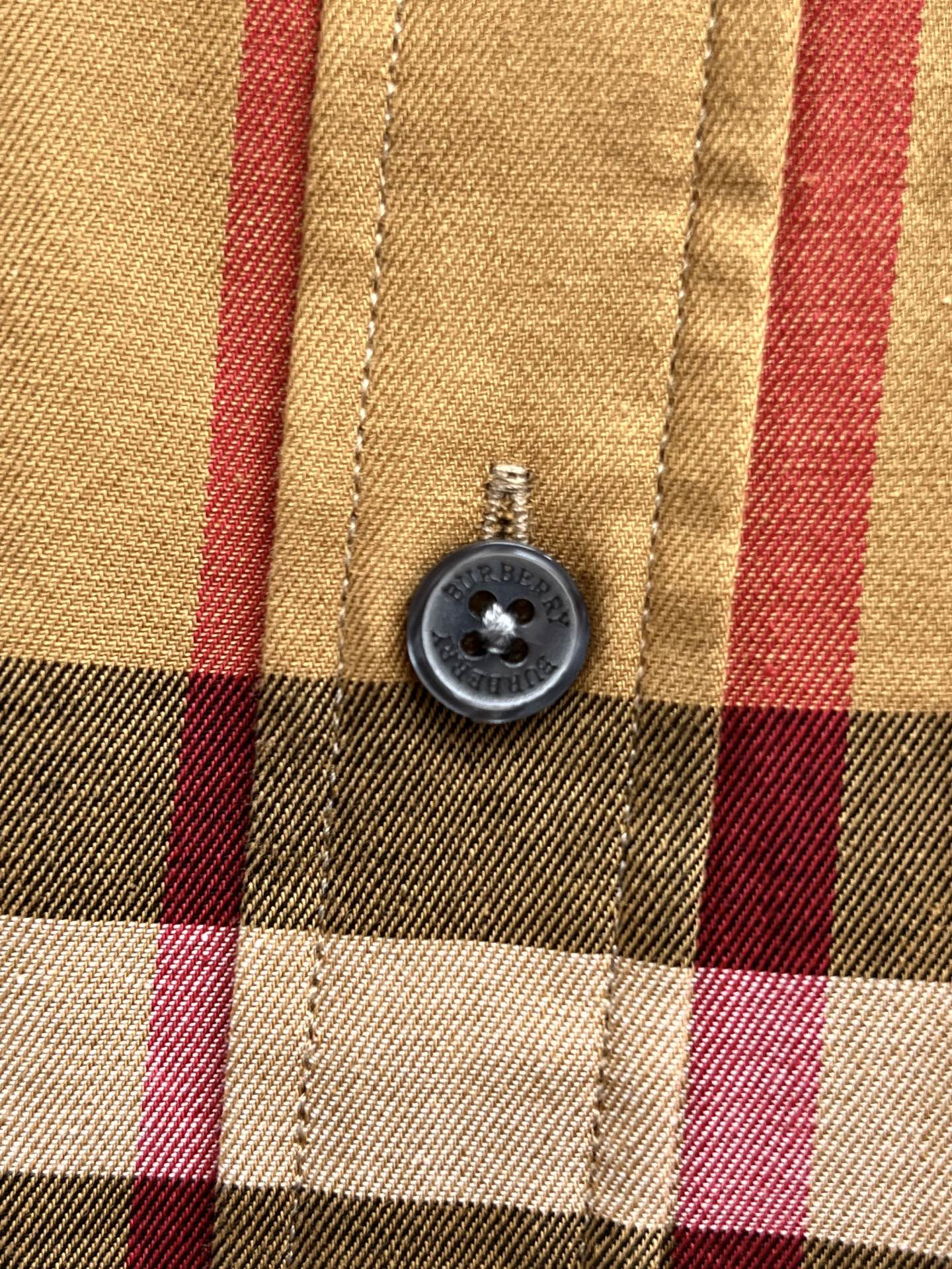 Round button on plaid long-sleeve shirt front with stitched placket