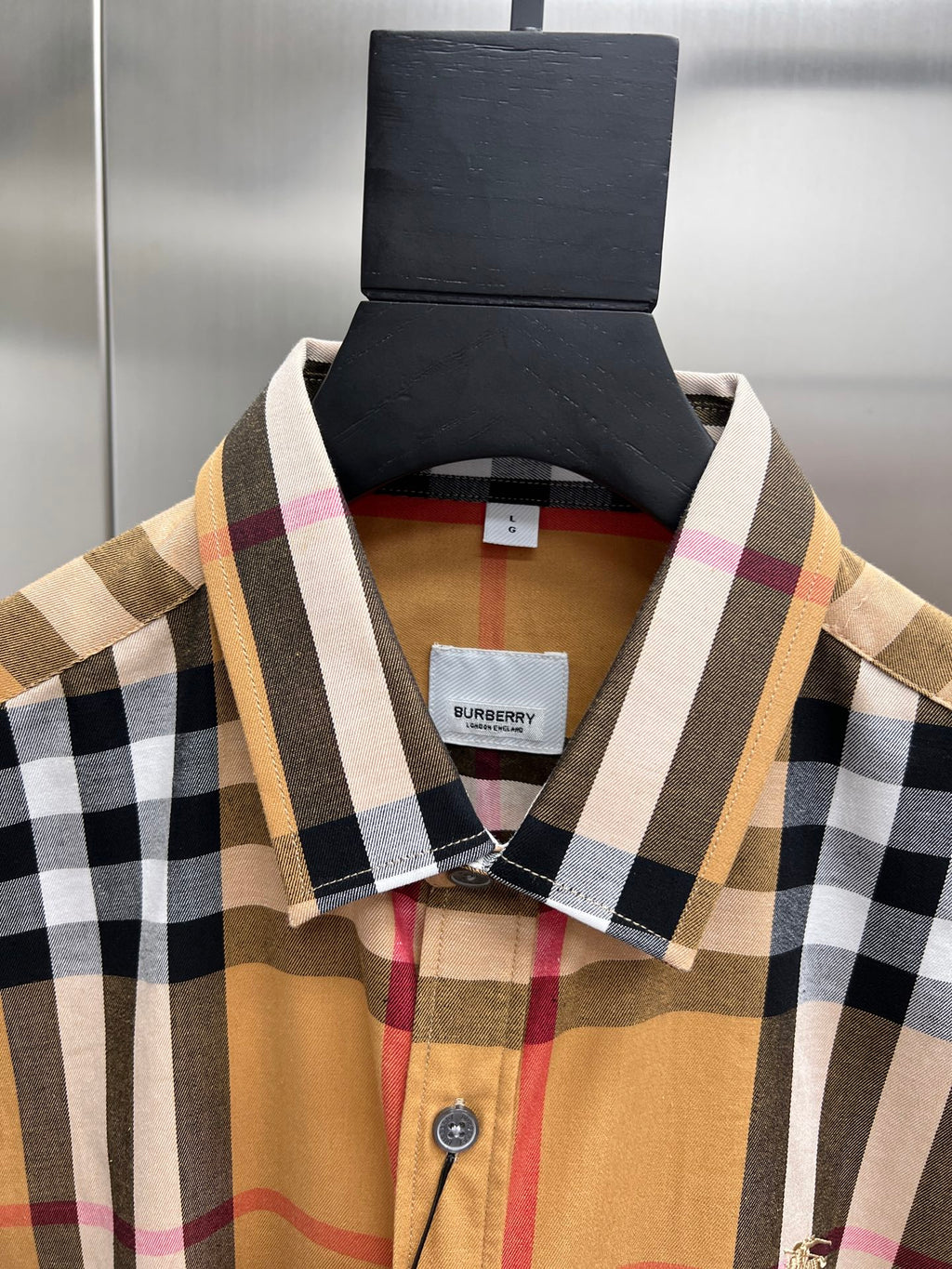 Long-sleeve plaid shirt collar close-up with brand tag and button placket
