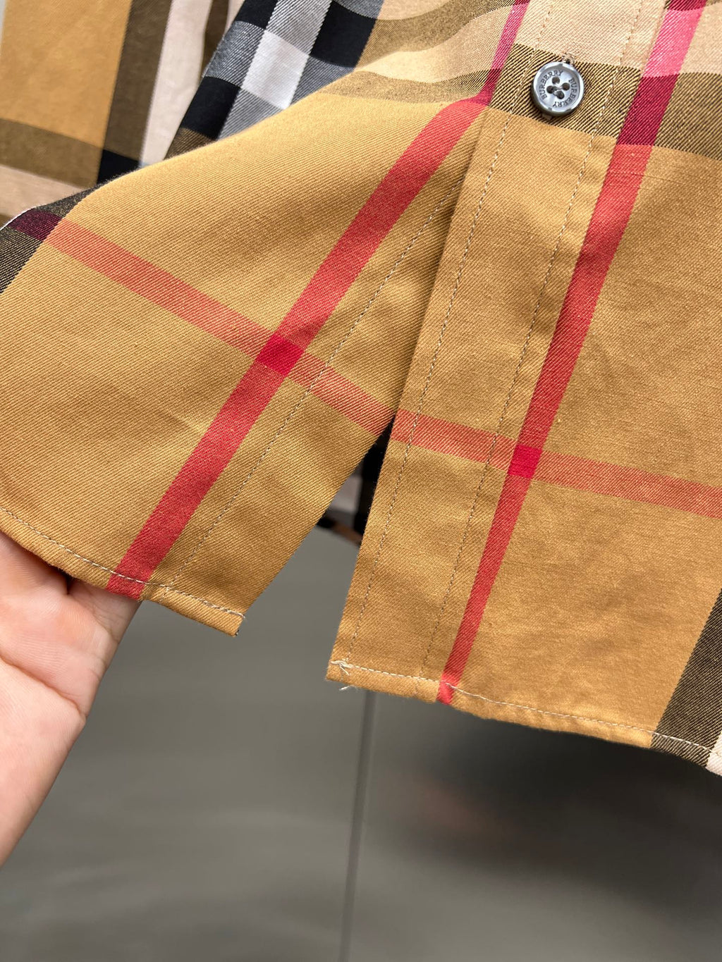 Burberry long-sleeve shirt cuff with button and tan, red, black plaid