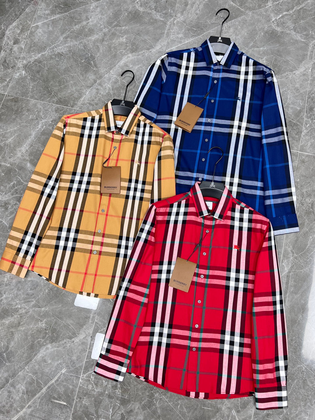 Set of three plaid long-sleeve shirts on hangers, red, blue, and beige