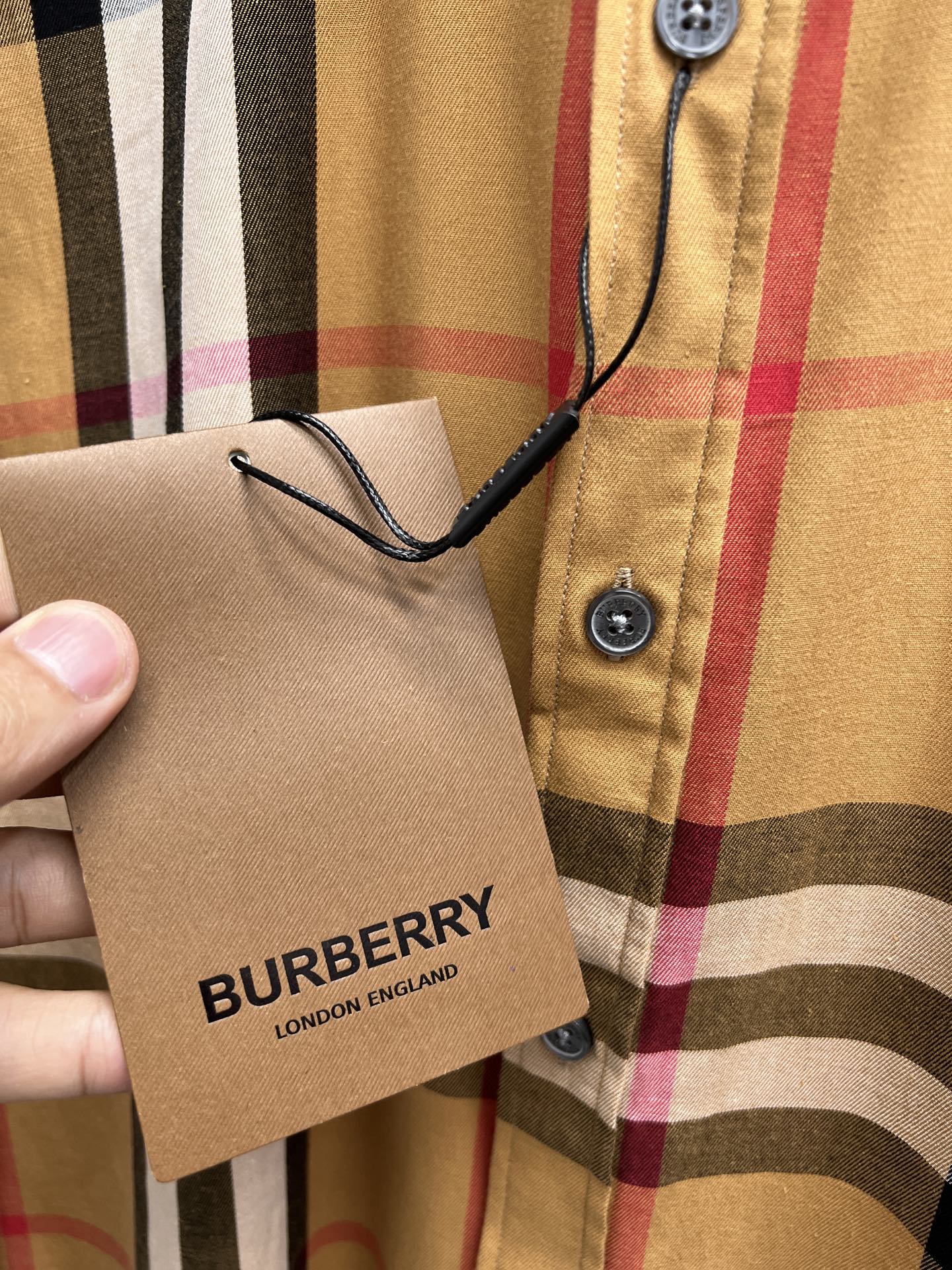 Plaid long-sleeve shirt with hang tag held near button placket