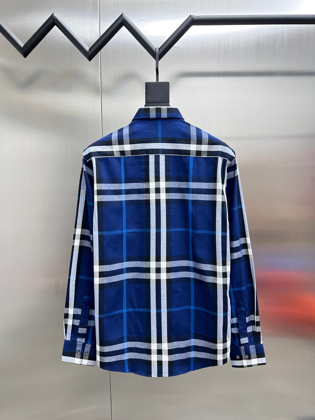 Long-sleeve button-up shirt in blue and white plaid, back view on hanger