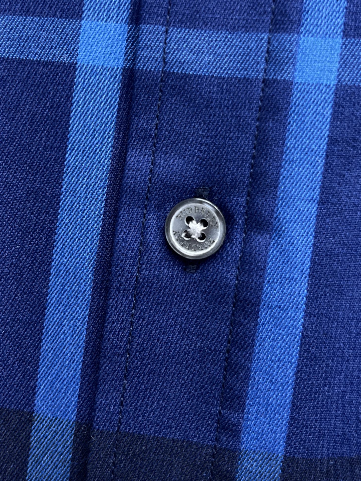 Round metal button on blue and white plaid shirt placket