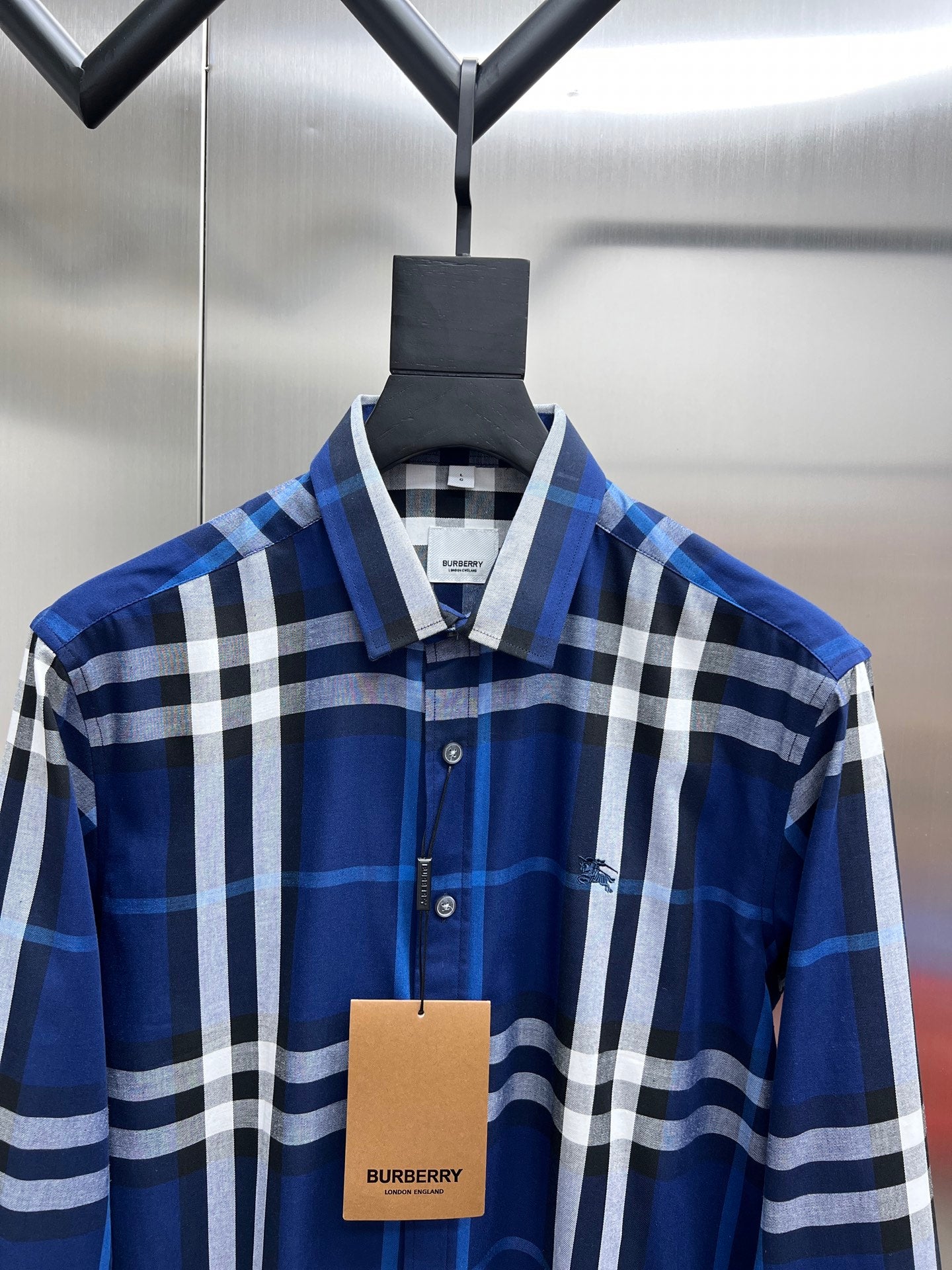 Blue and white plaid long-sleeve button-up shirt with pointed collar on hanger