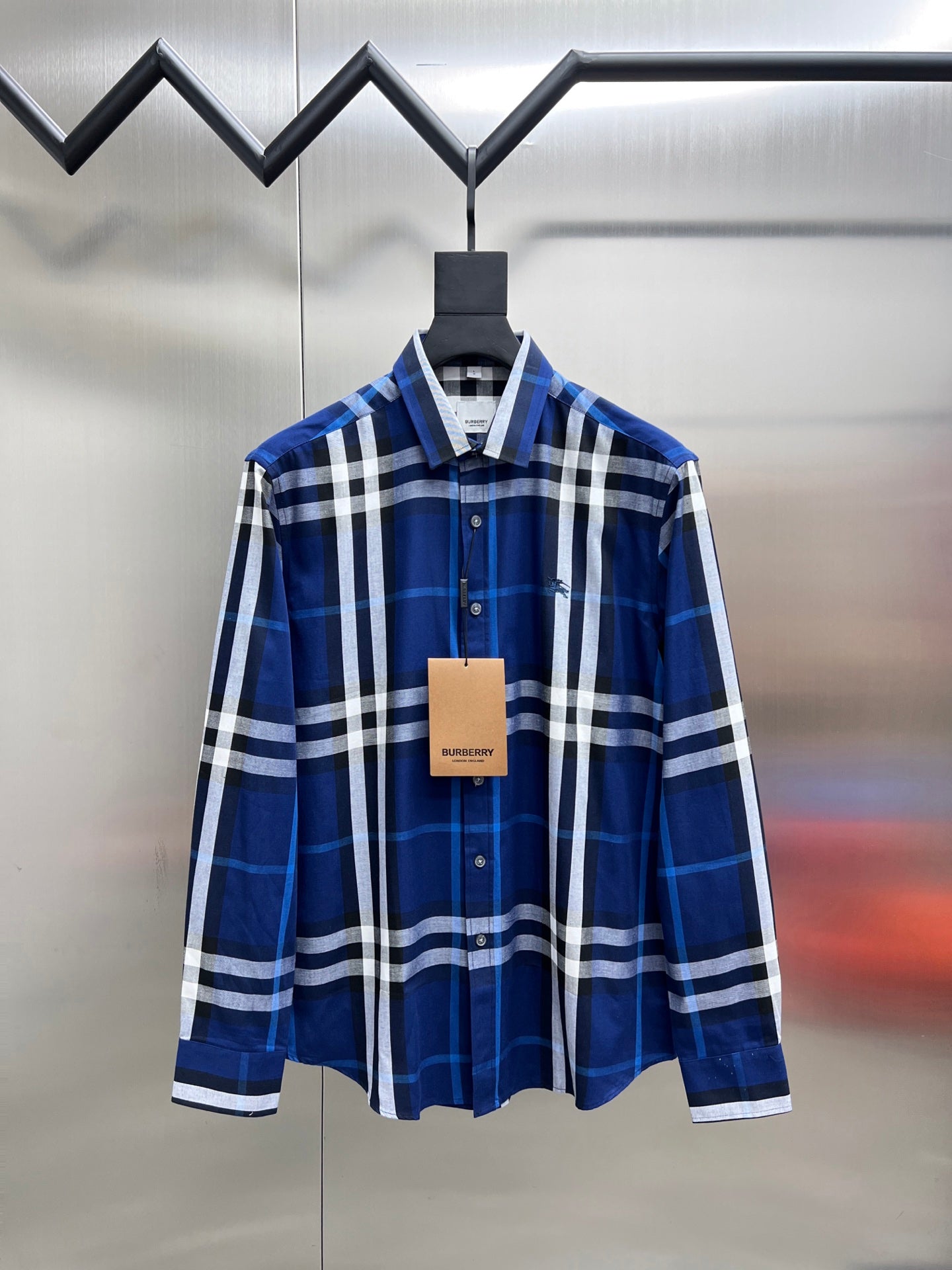 Long-sleeve button-up shirt in blue and white plaid, front view on hanger