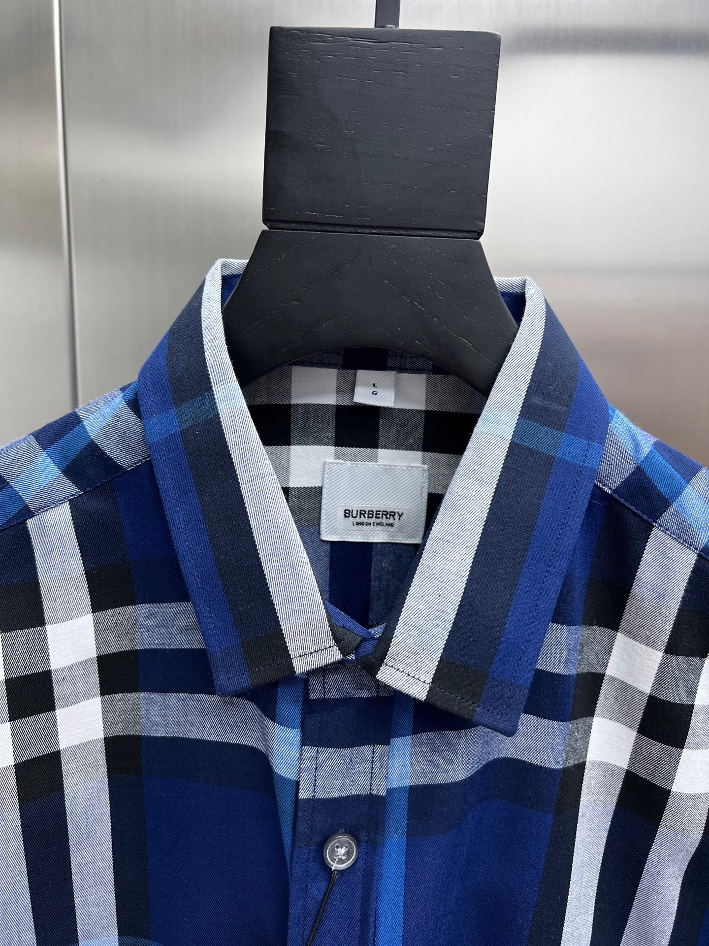 Blue and white plaid shirt collar with button placket, on hanger