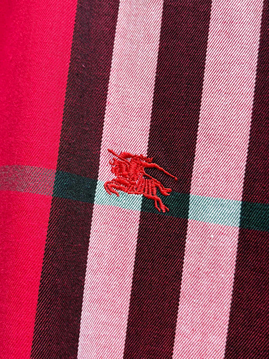 Embroidered red horse-and-rider logo on red plaid fabric