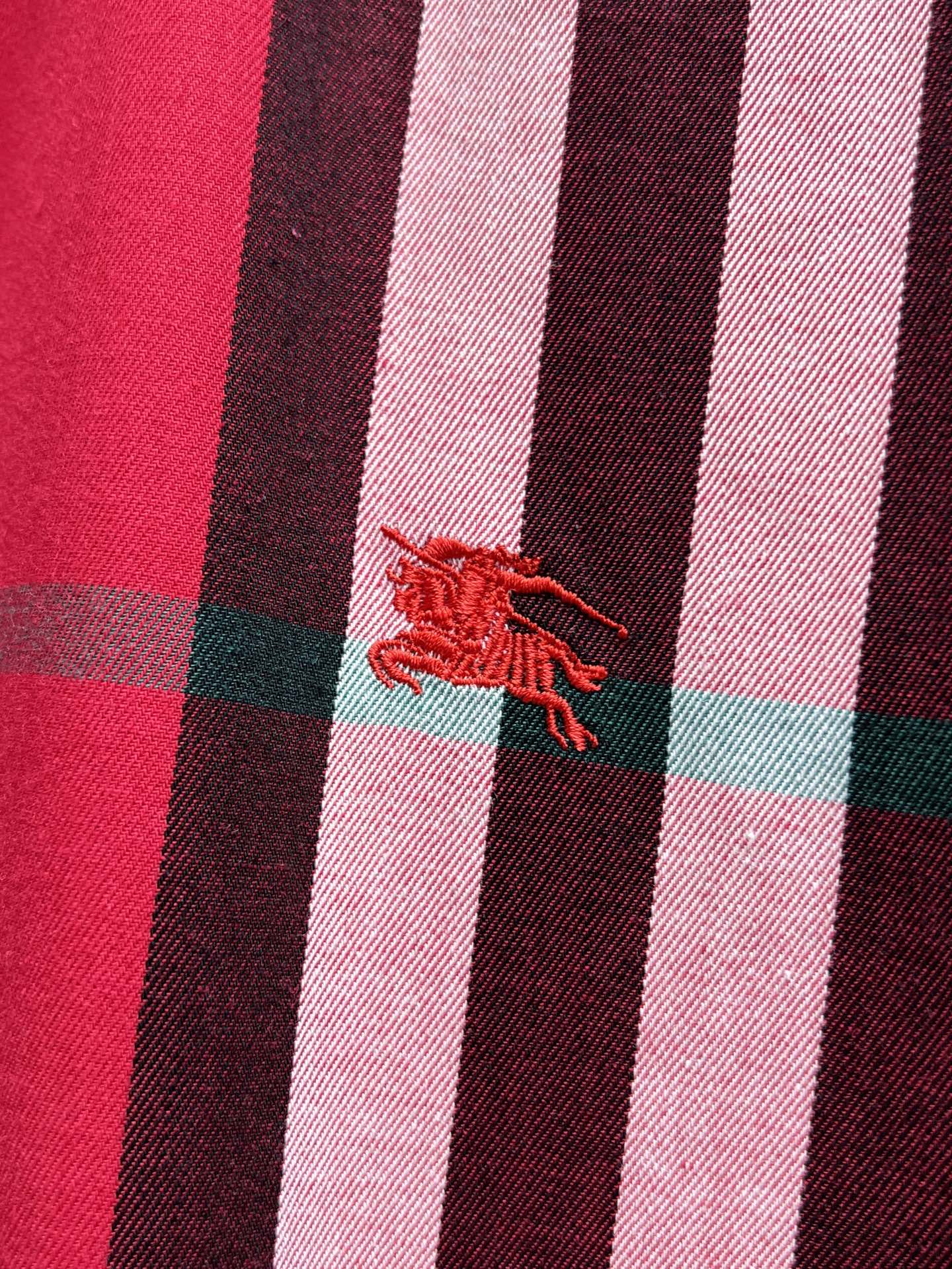 Embroidered red horse-and-rider logo on red plaid fabric