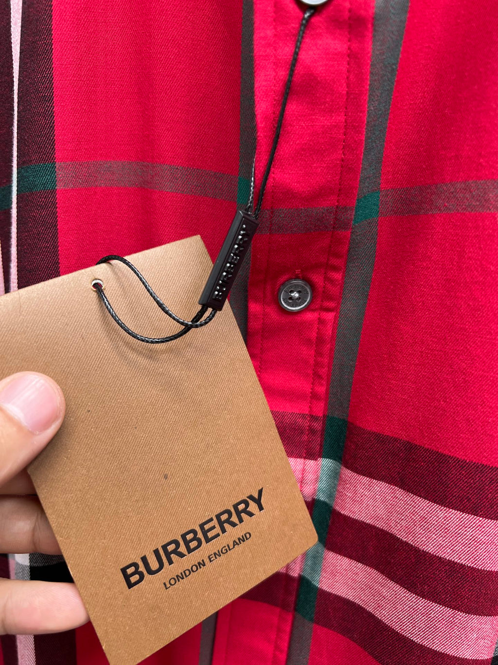 Burberry hang tag on red and black plaid button-up shirt front