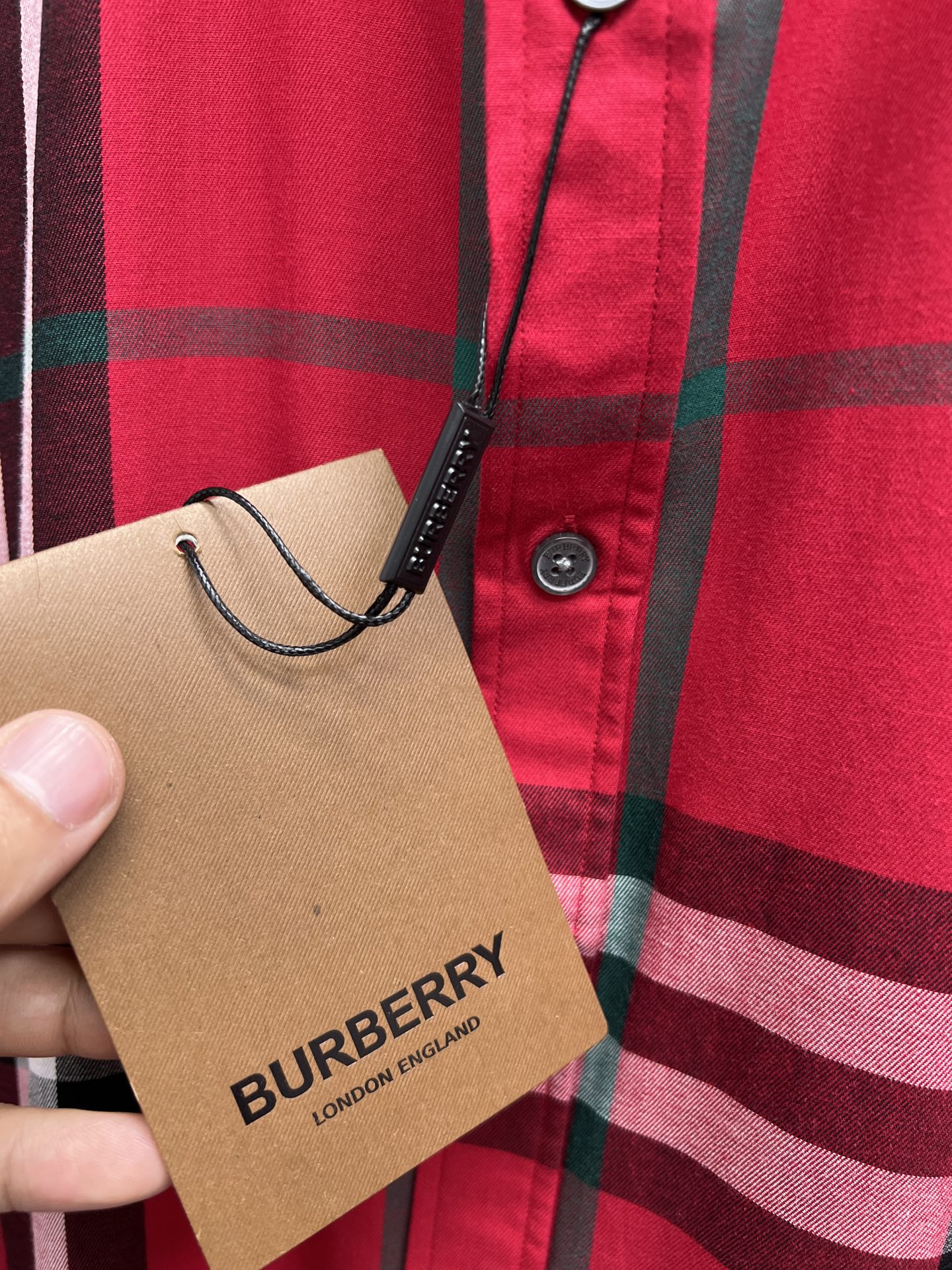 Burberry hang tag on red and black plaid button-up shirt front