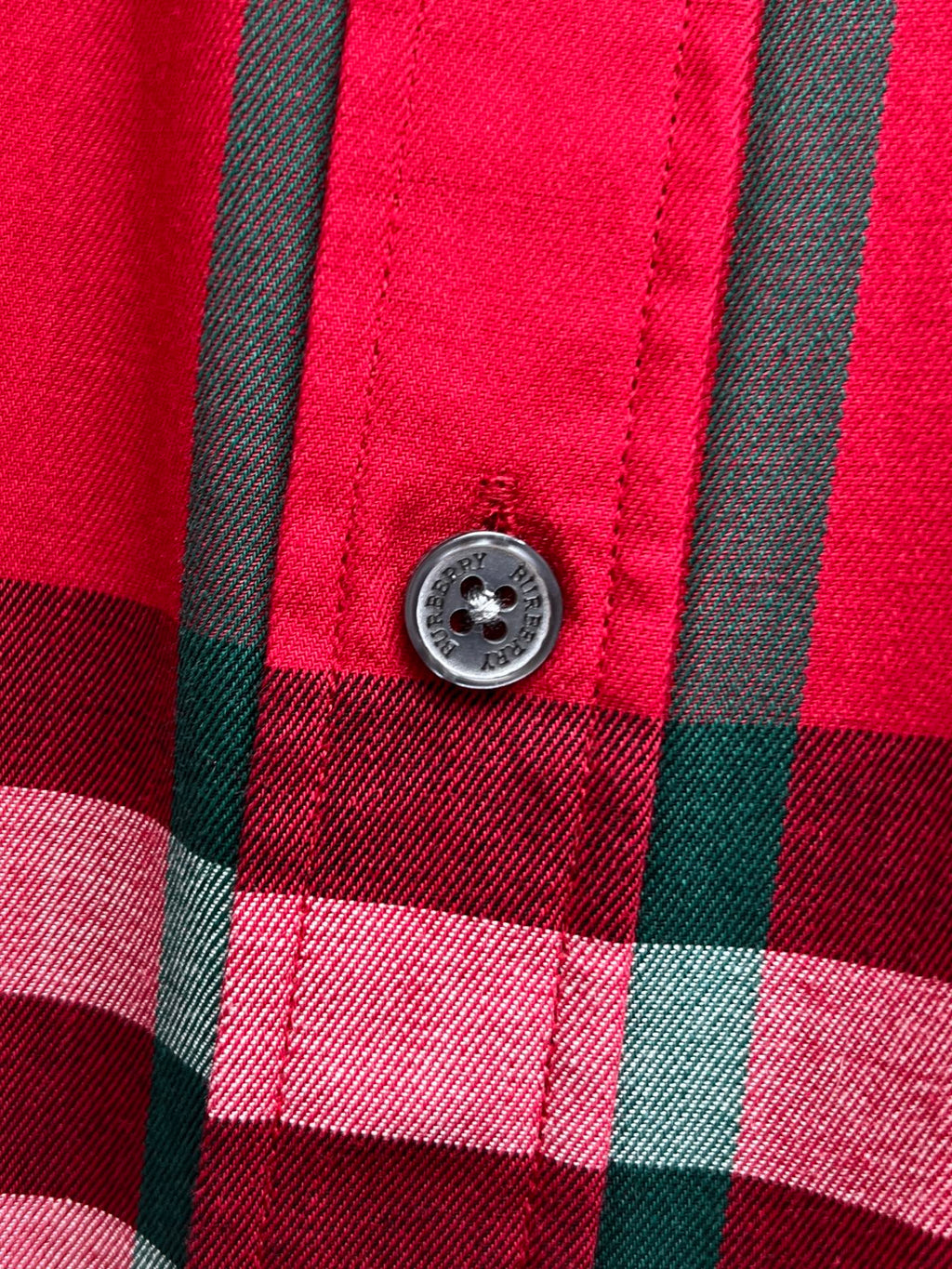 Round button on red and black plaid button-up shirt placket