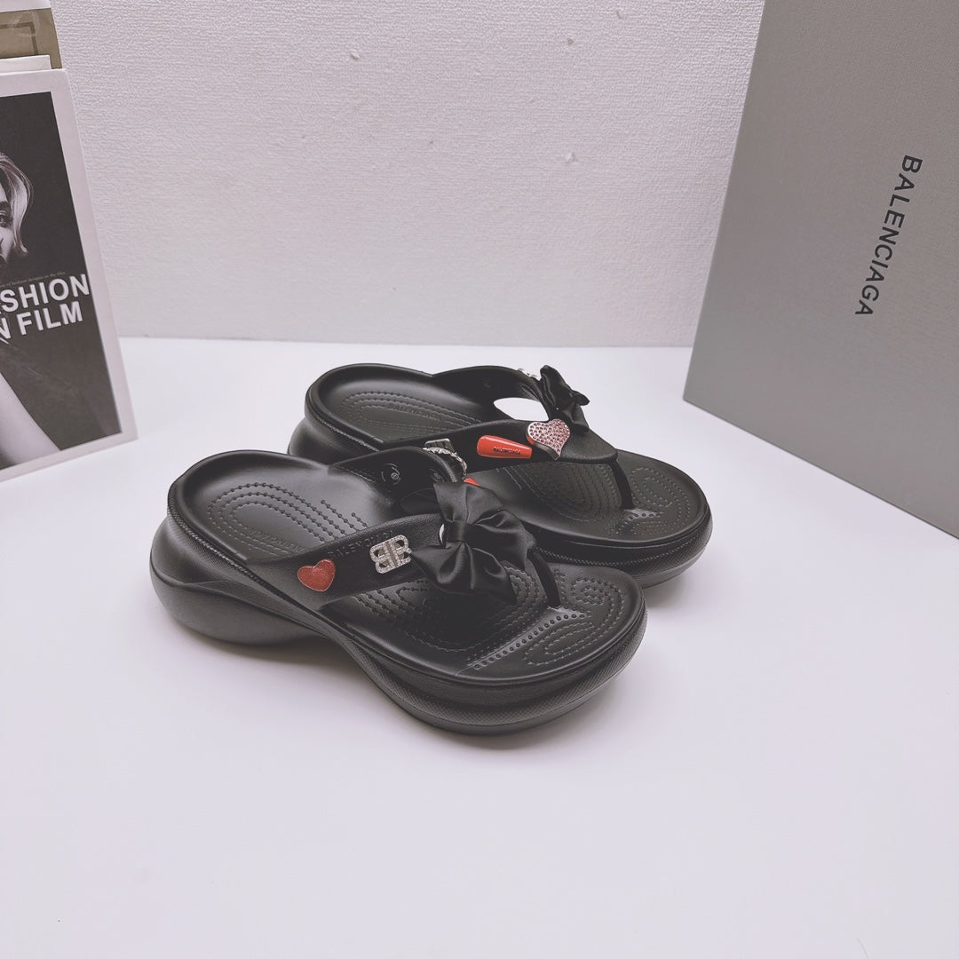 Black Balenciaga sandals featuring bow detail, heart patch accents, and textured outsole