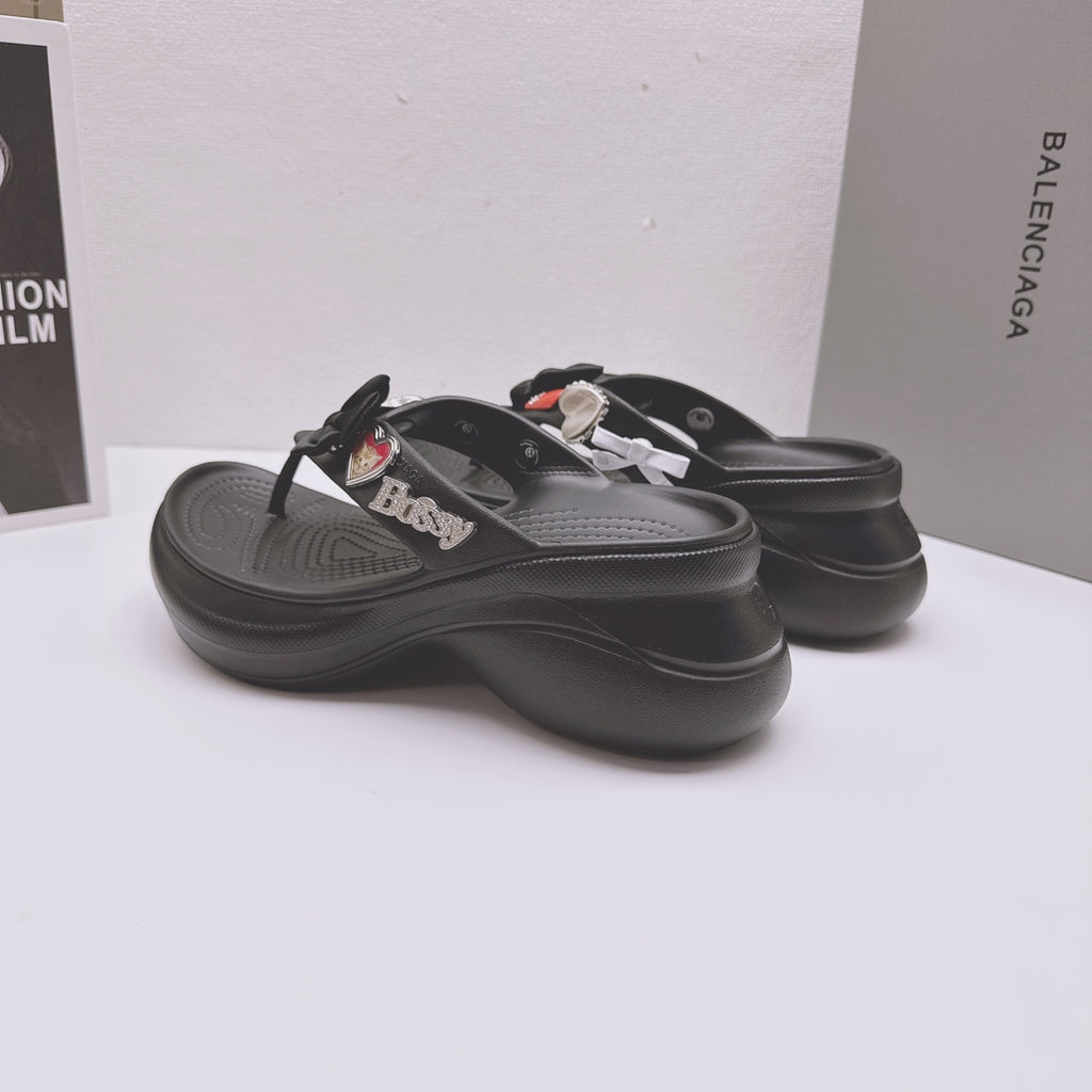 Black Balenciaga sandals with bow and heart patch decorations, angled side view