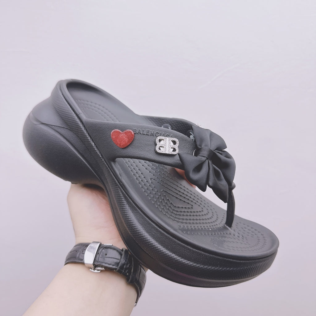 Black Balenciaga sandals with bow strap, heart patch, and contoured footbed profile