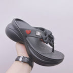 Black Balenciaga sandals with bow strap, heart patch, and contoured footbed profile