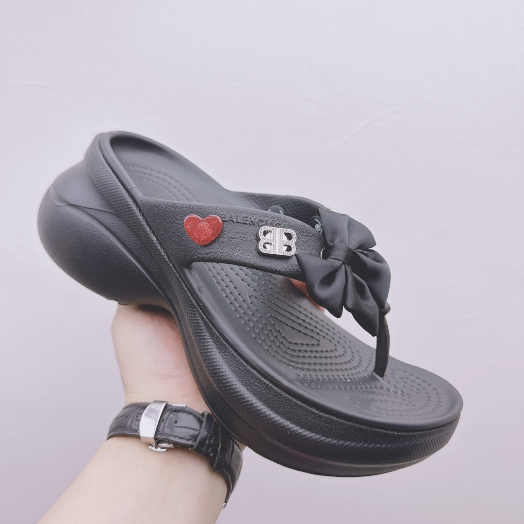 Black Balenciaga sandals with bow strap, heart patch, and contoured footbed profile