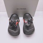 Black Balenciaga sandals, front view with bow straps, heart patch charms, and thick sole