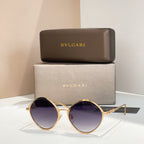Gold round sunglasses with dark purple-tinted lenses and slim metal arms.