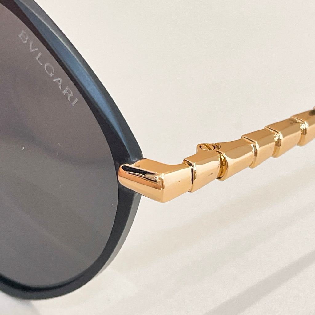 Gold eyeglass temple arm with engraved details and hinge hardware.
