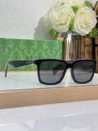 Black Gucci square sunglasses with dark tinted lenses and thick frames