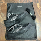 Black Balenciaga unisex sneakers with white logo, shown on drawstring pouch