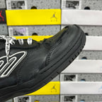Black sneaker side view with silver logo and textured toe cap
