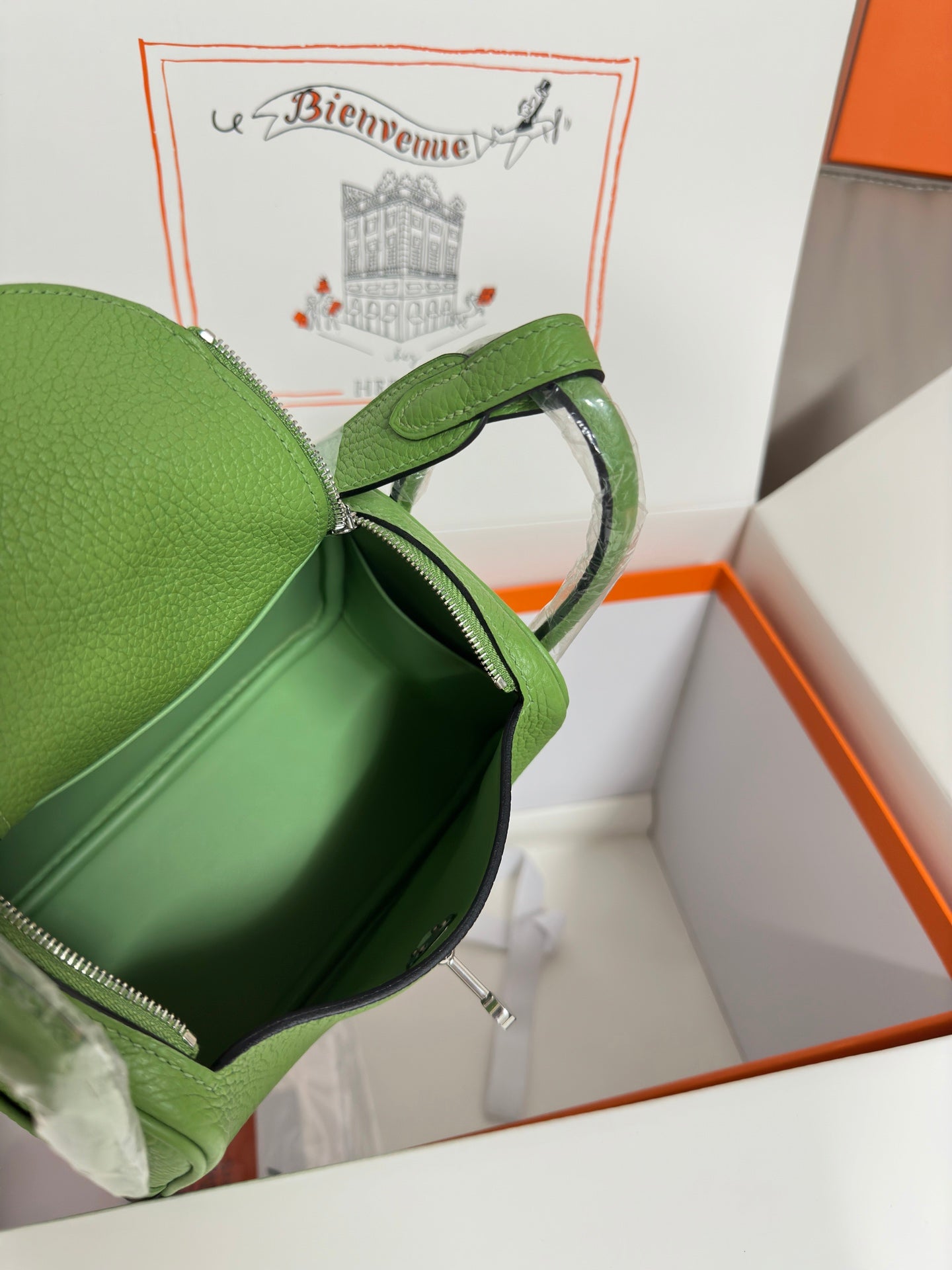 Green leather Hermes handbag showing interior with zip opening and top zipper pull