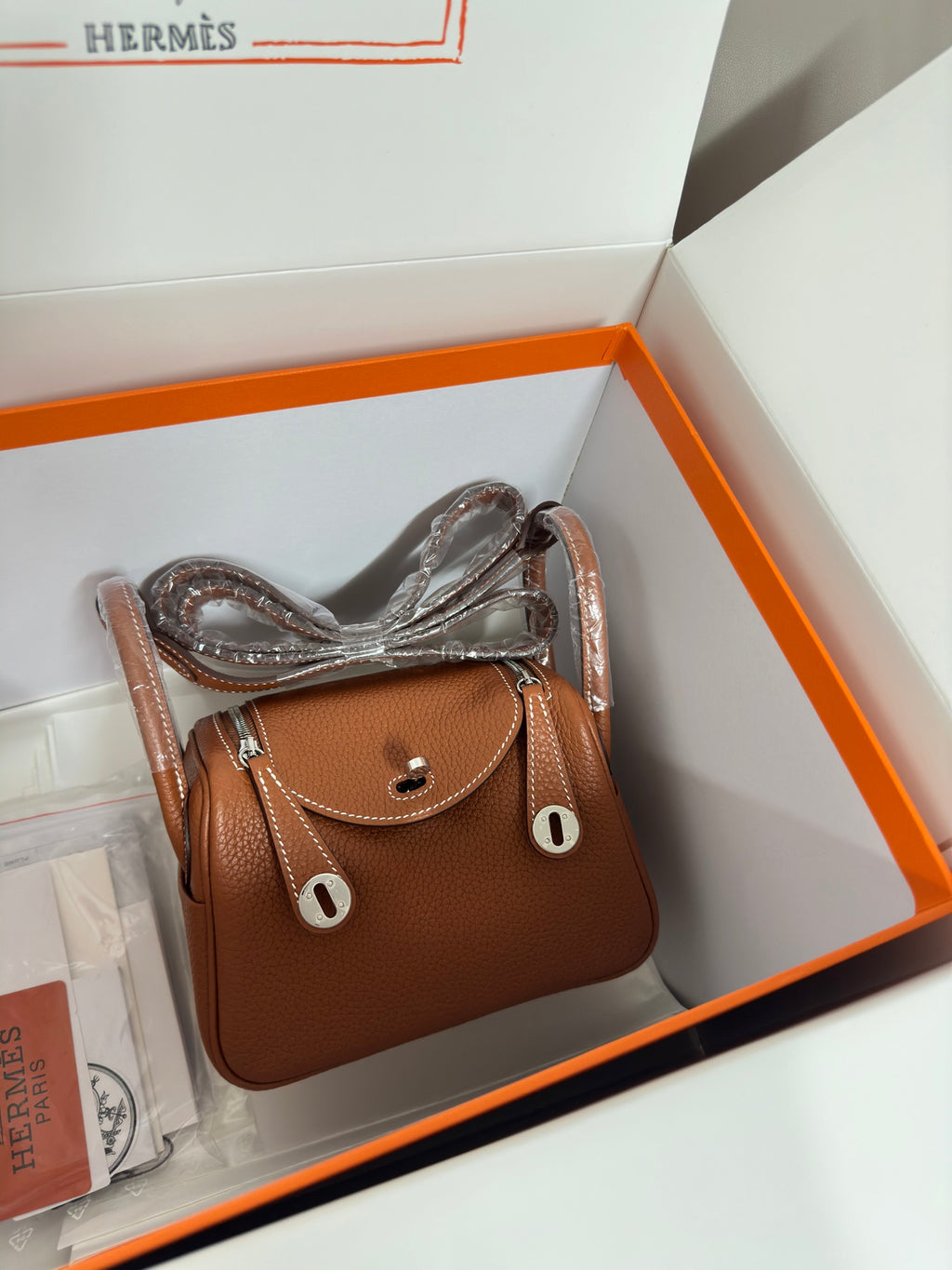 Hermes mini leather handbag in tan with front flap closure and short top handles, silver hardware