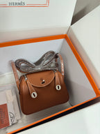 Hermes mini leather handbag in tan with front flap closure and short top handles, silver hardware