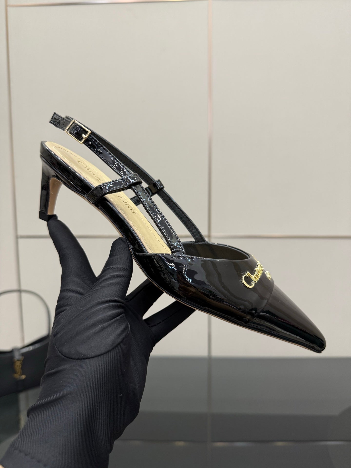Black patent slingback heel with gold logo buckle and strap detail