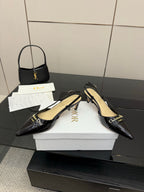 Black pointed-toe slingback heels with cream insole and gold logo strap