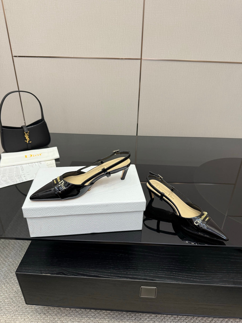 Black pointed-toe slingback heels with gold logo hardware and stiletto heel