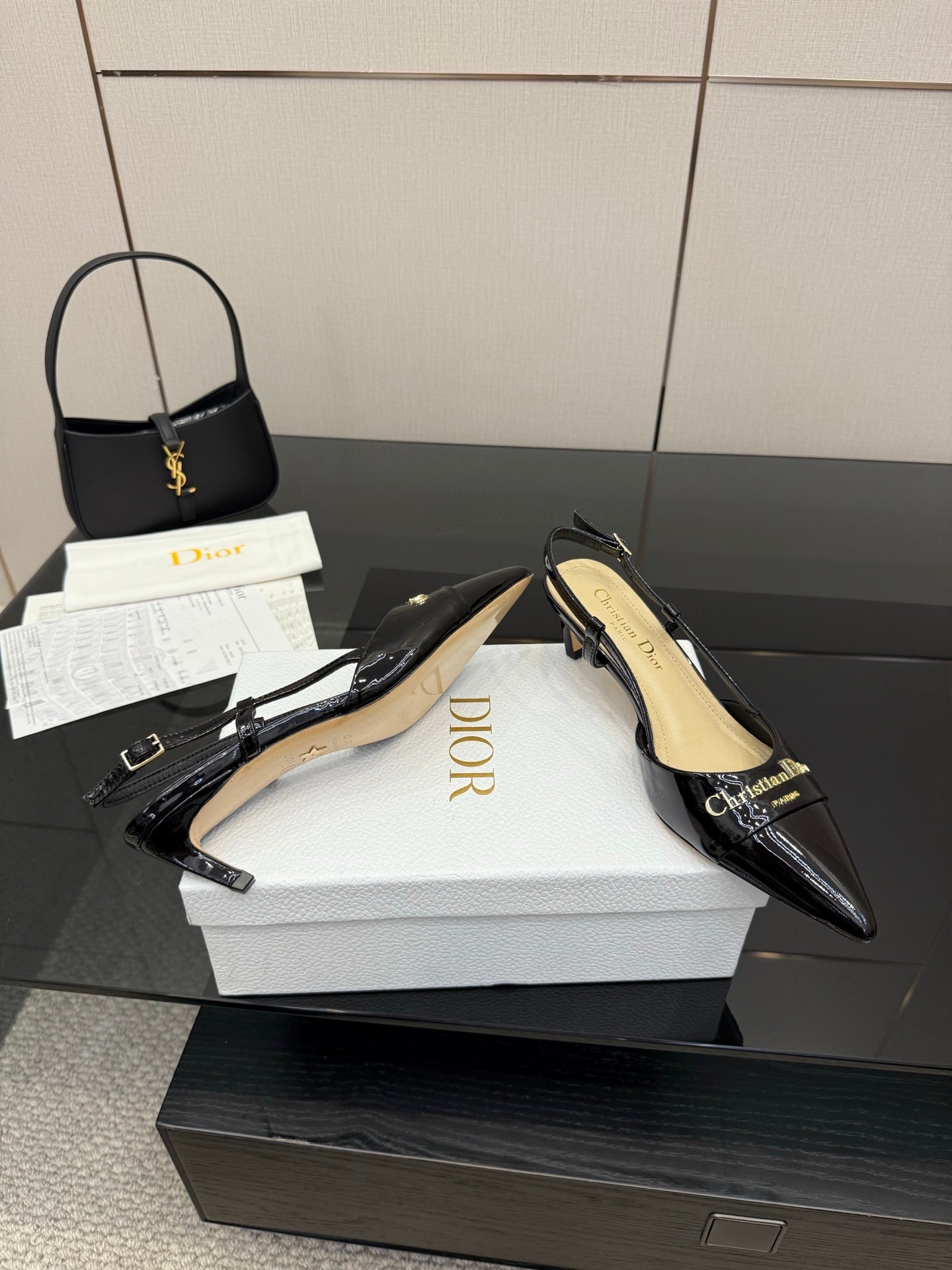 Black pointed-toe slingback heels with gold logo and cream lining