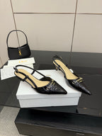 Black pointed-toe slingback heels with gold trim and logo strap, side view