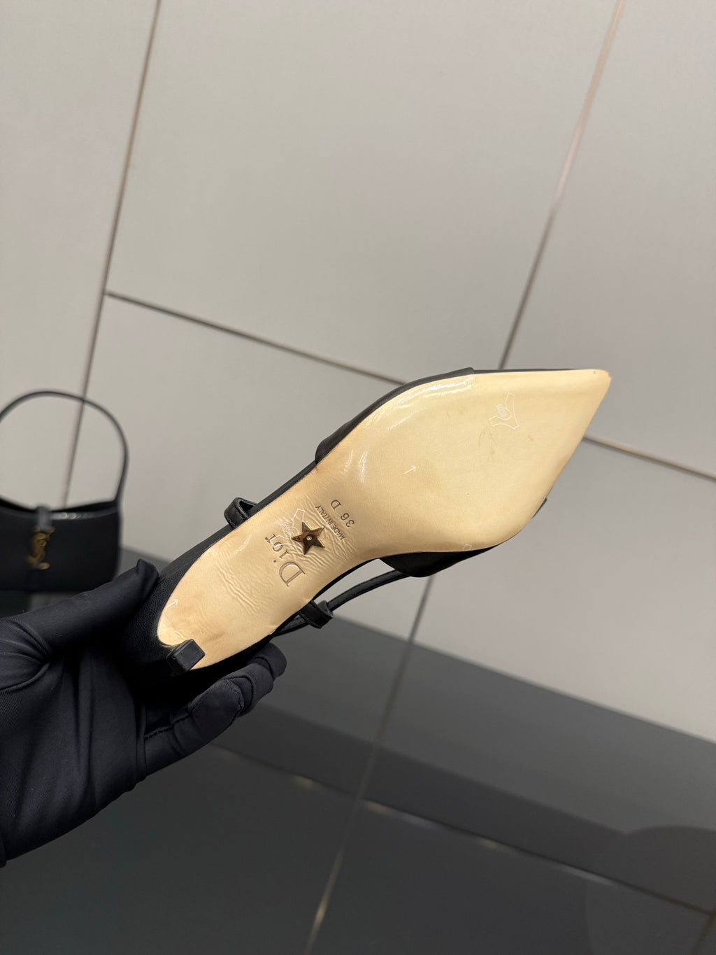 Black slingback pump in hand showing beige insole, pointed toe, thin strap