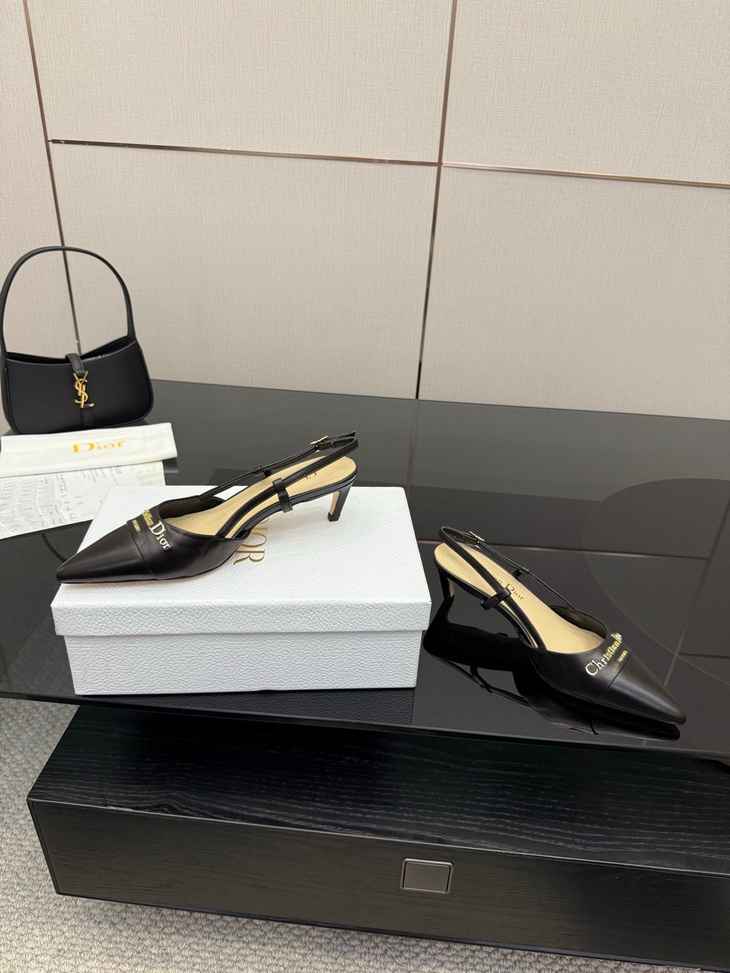 Black pointed slingback pumps with thin ankle straps and gold logo hardware