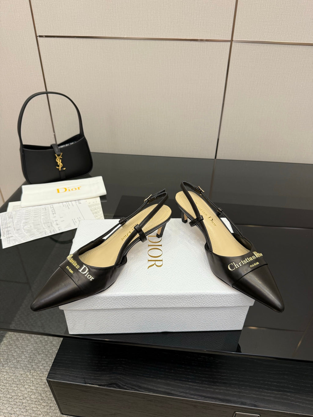Black slingback pumps on white shoe box, pointed toe and gold hardware