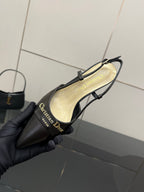 Close-up of black slingback pump held in hand, beige insole and thin straps