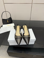 Black pointed-toe slingback pumps with gold logo detail and low heel