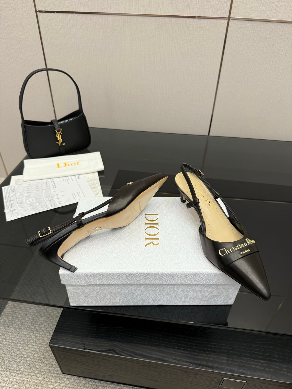 Black pointed-toe slingback pumps with gold emblem, beige lining and straps
