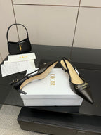 Black pointed-toe slingback pumps with gold emblem, beige lining and straps