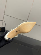 Ivory pointed-toe slingback heel viewed from sole side in gloved hand