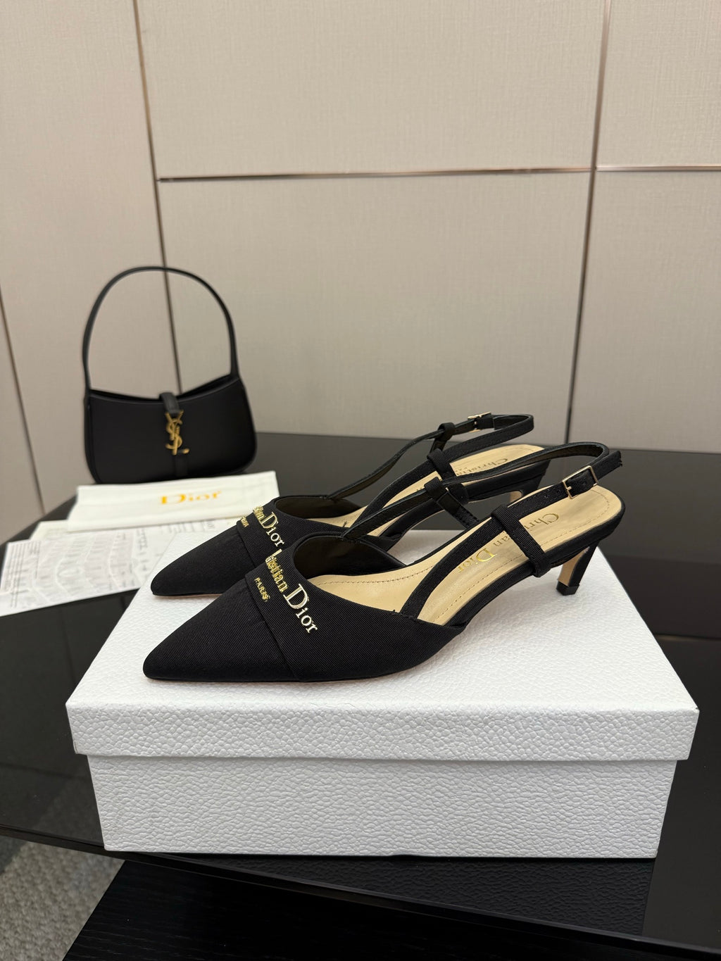 Black slingback pumps with slim heel, ankle straps, and gold logo