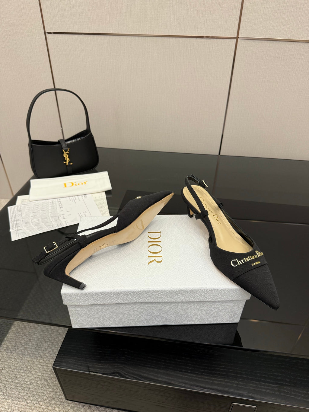 Black pointed slingback heels with cream footbed and gold logo